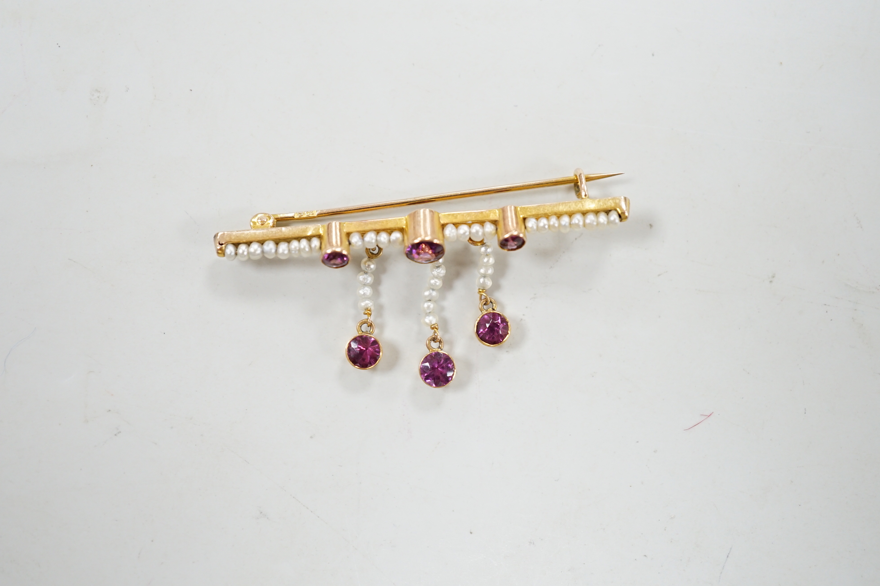 An early 20th century yellow metal, garnet and seed pearl cluster set drop bar brooch, 43mm, gross weight 2.1 grams.
